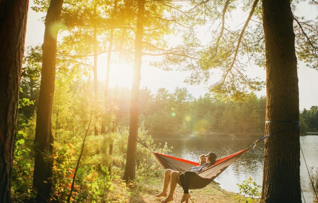 Pärchen in einer Hängematte an einem See in der Nähe eines Campingplatzes