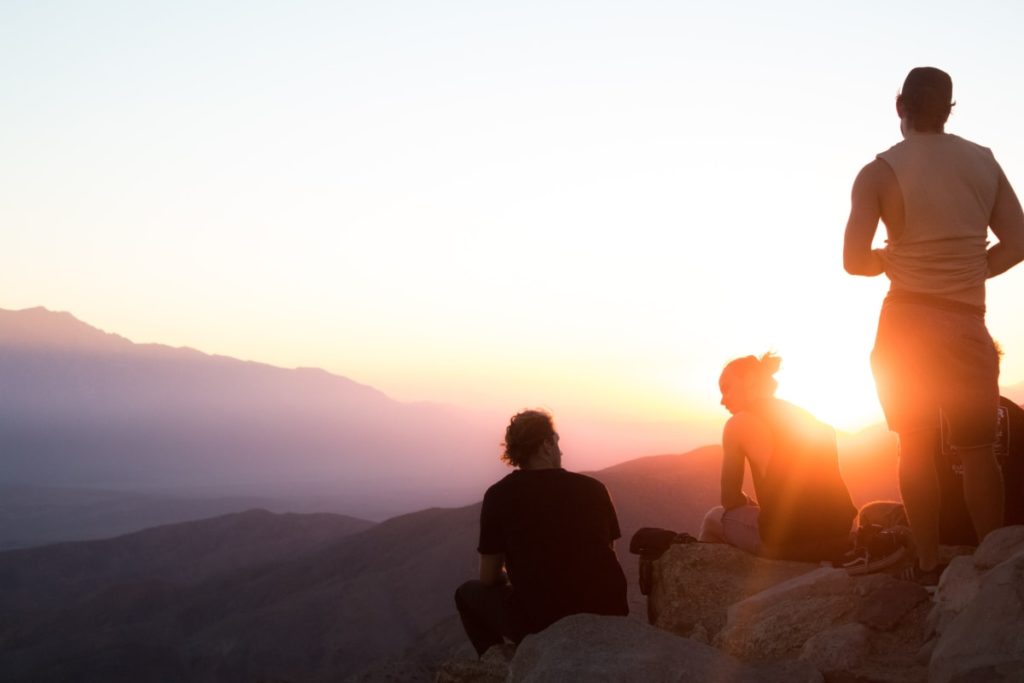 Gruppe von Menschen in einer Gruppenreise auf einem Berg in einem hohen Gebirge bei Sonnenuntergang