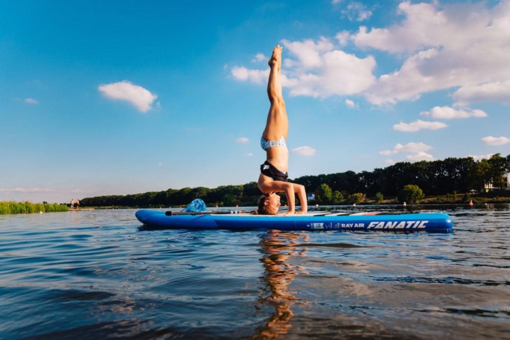 Best standup paddle boarding spots in germany woman doing a head stand on a paddle board on the Werder lake in Bremen