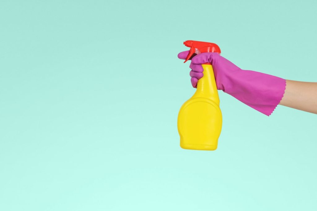 a hand holding up a cleaning spray 