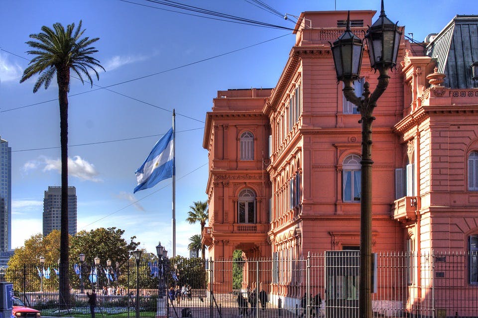 Argentinische Flagge, Palme und Laterne vor großem Gebäude
