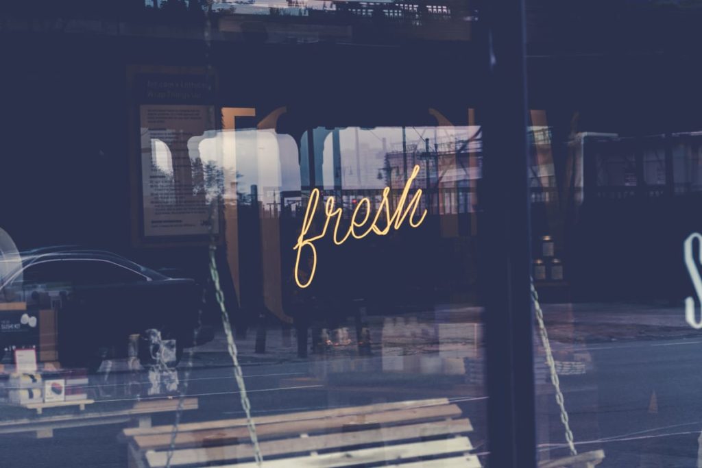 a yellow neon sign reading fresh