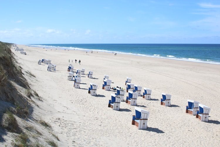 places to visit in Germany Sylt beach sea, a beach with the blue sea in the background and little sun hats
