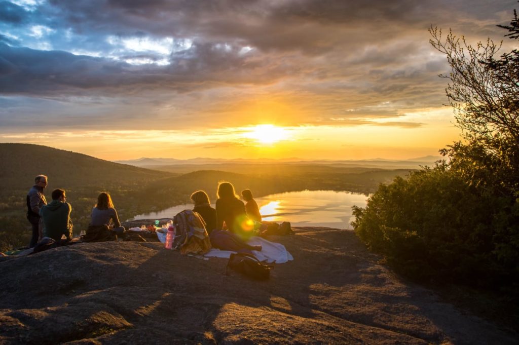 A group of friends having a picnic watching the sunset on a stone cliff