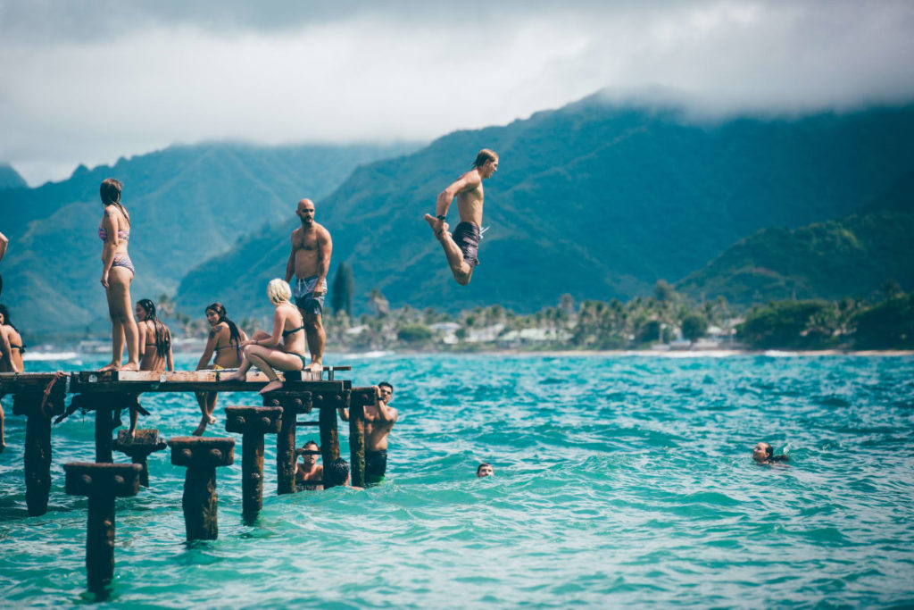 Traveling after corona on a dock and someone jumping in the blue sea