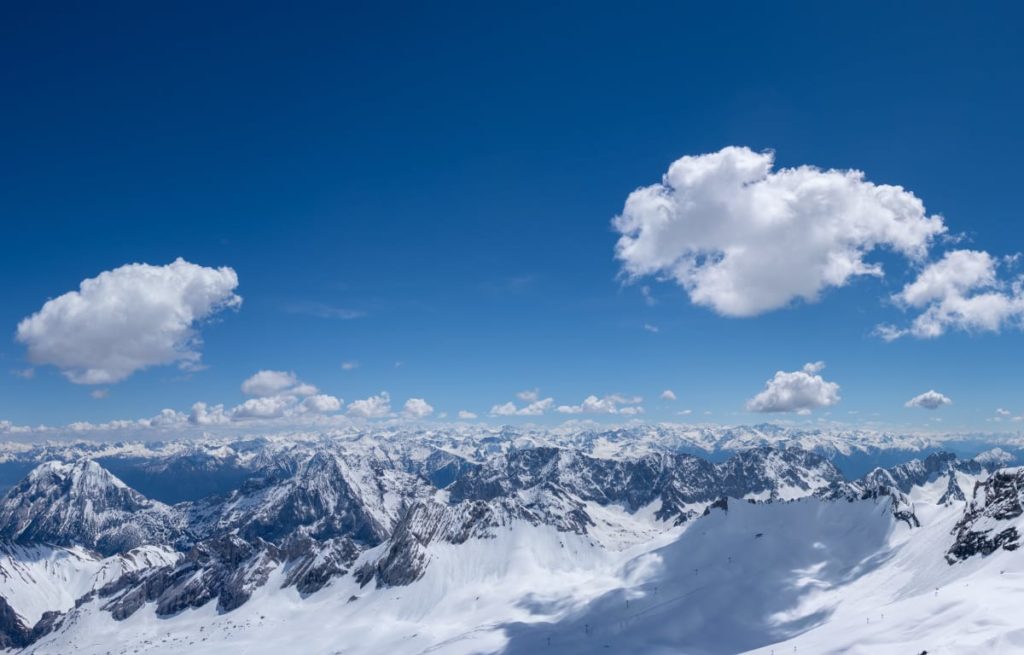 Die Zugspitze in Bayern mit Schnee  bedeckt und blauem Himmel. Dort gibt es Camping in Iglus