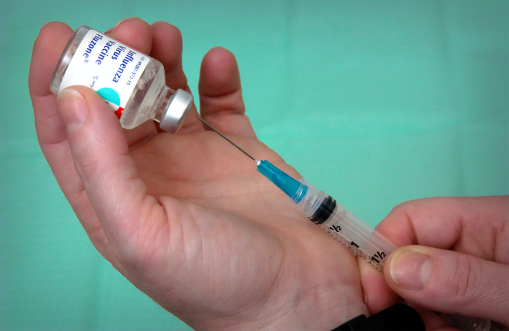 Reiseplanung: Impfen - eine Hand hält eine Spritze 