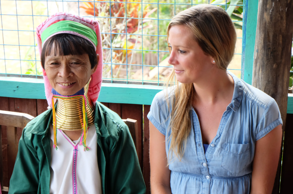 Steffi schaut Frau mit traditionellem Kopfschmuck und Ringen um den Hals von der Seite an in Myanmar