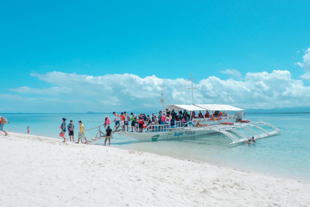 a travel mistake on the beach with turquoise blue water and blue skies with people getting off a boat.