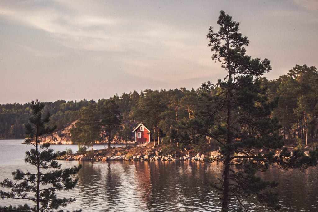 Rote Blockhütte am See in Schweden.