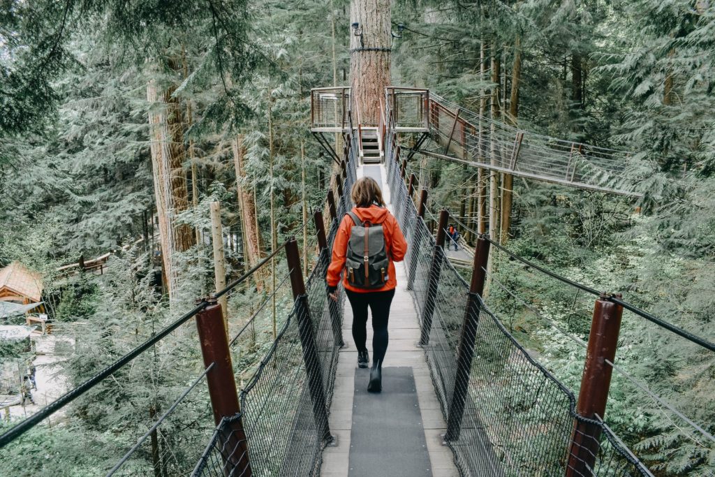 woman walking on a black bridge through the woods of top spot Vancouver 