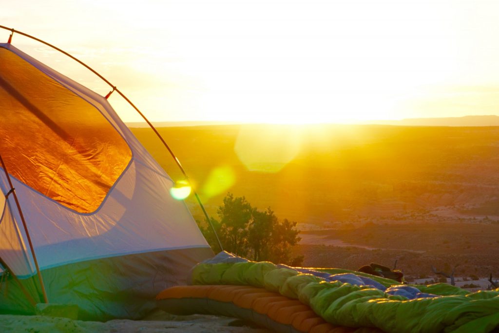 the best travel gifts: a sleeping back and a tent outside. 