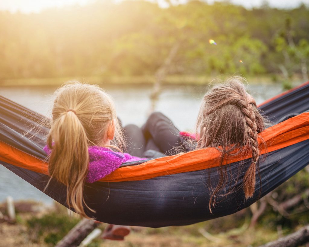 how to travel around the world on a budget with 2 girls laying on a hammock.