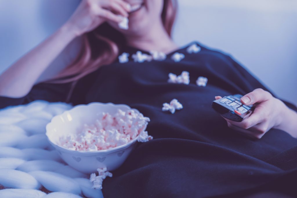 a woman eating popcorn while watching a movie during winter lockdown