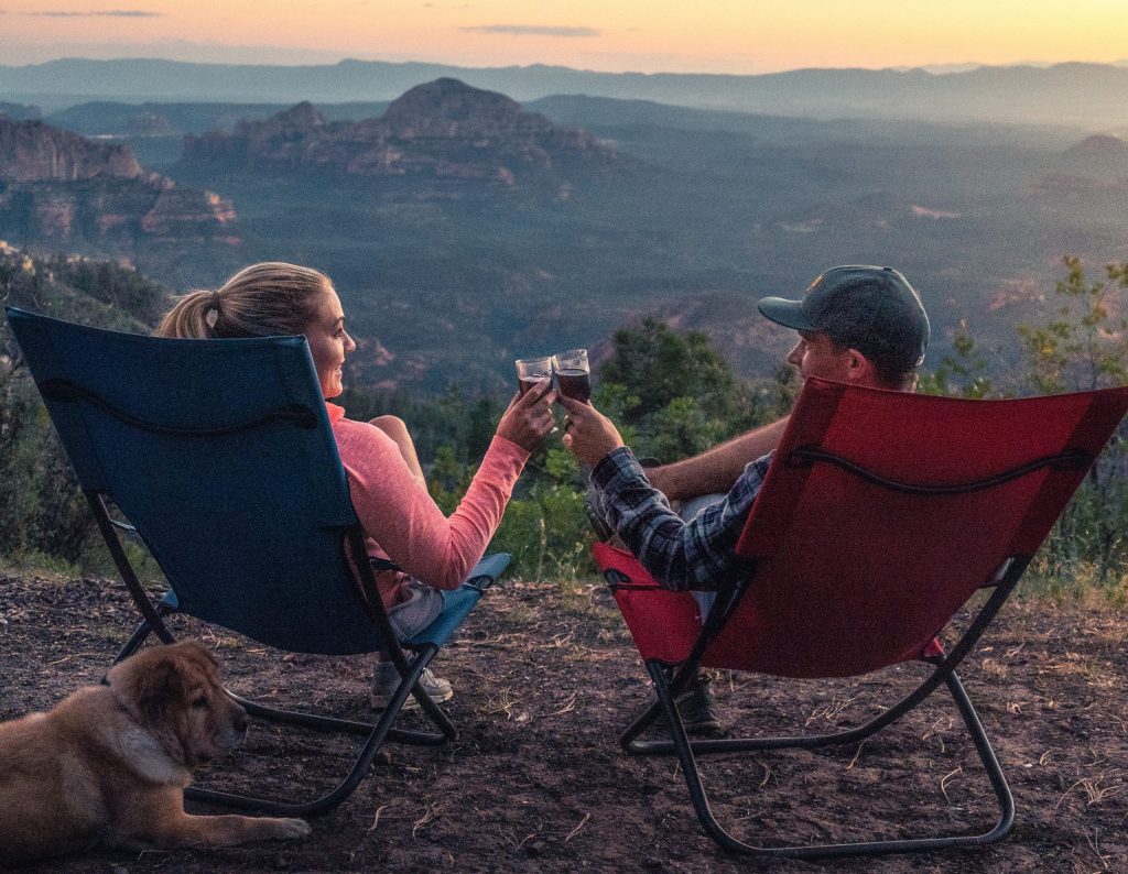 Ein Mann und eine Frau, die mit Wein anstoßen und während ihres Camping Trips Amazon Music hören.