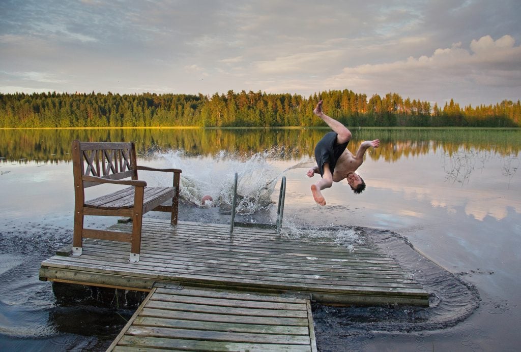 Ein Mann springt rückwärts in einen See in Finnland.