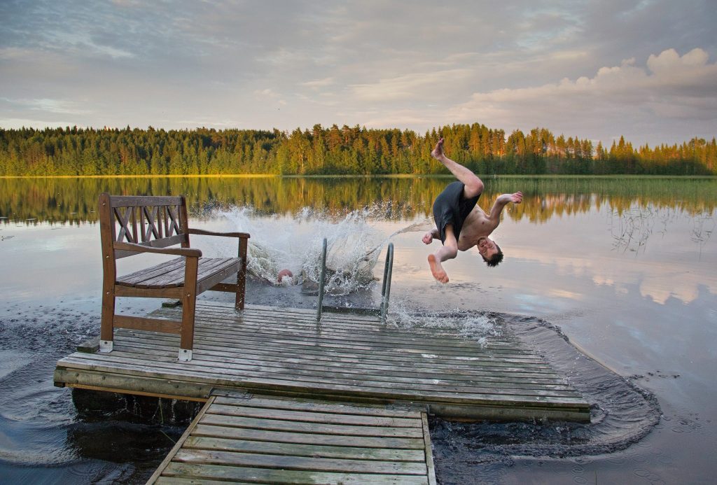 A man jumps backwards into a lake in Finland.