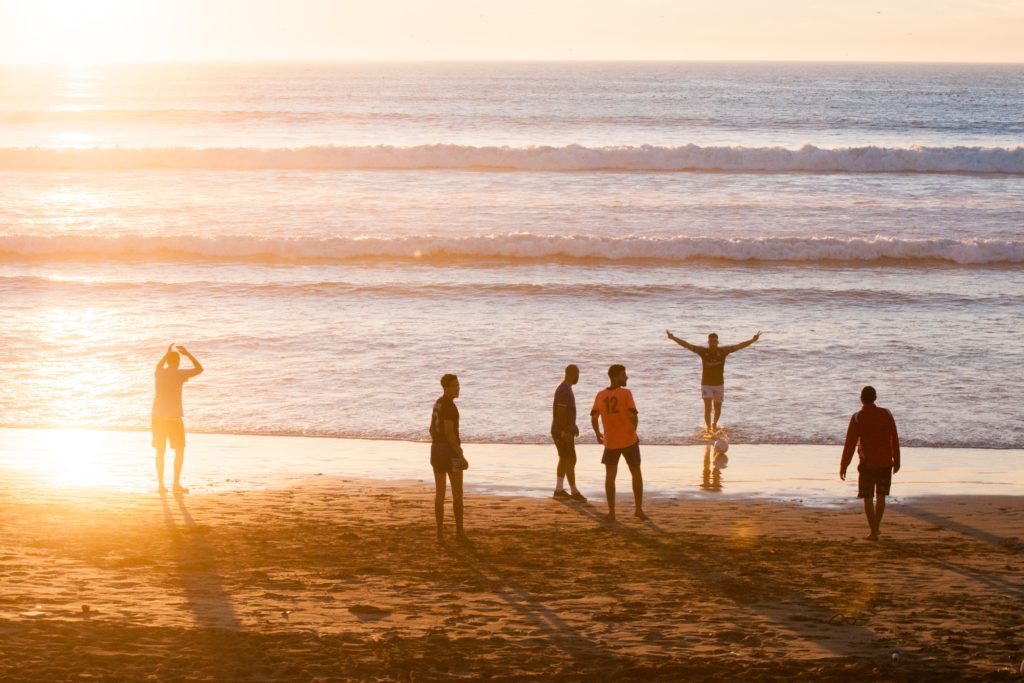 eine Gruppe von Männern die am Meer stehen, am Strand und Spaß haben