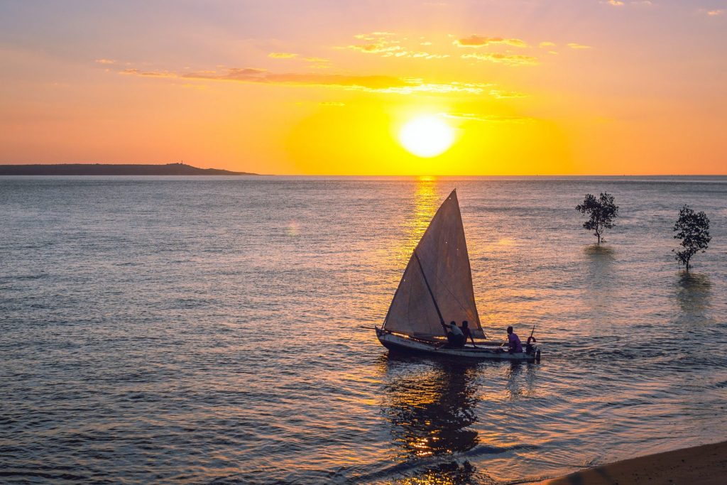 Segelboot mit Palmen auf dem Meer im Sonnenuntergang in Madagaskar.