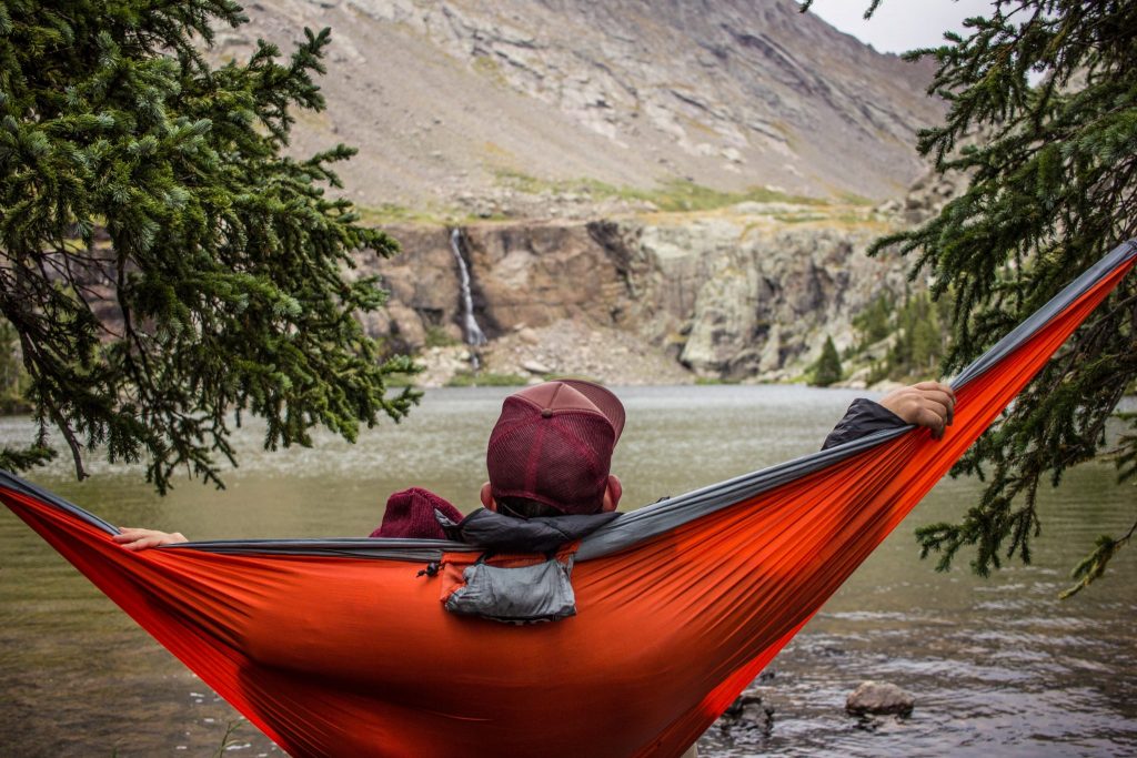 A man sits in a hammock - the perfect travel essential for outdoor trips.