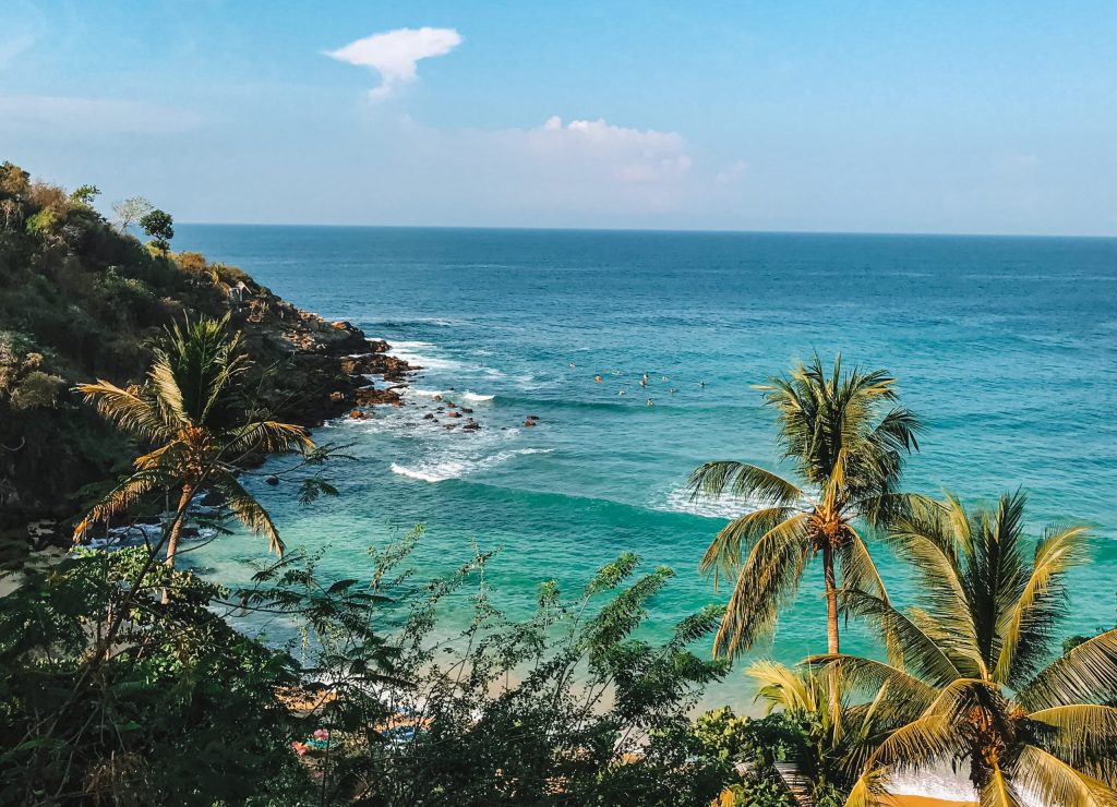 Of places you must visit in Mexico Puerto Escondido must be on your list. Blue water, palm trees and a cliff.