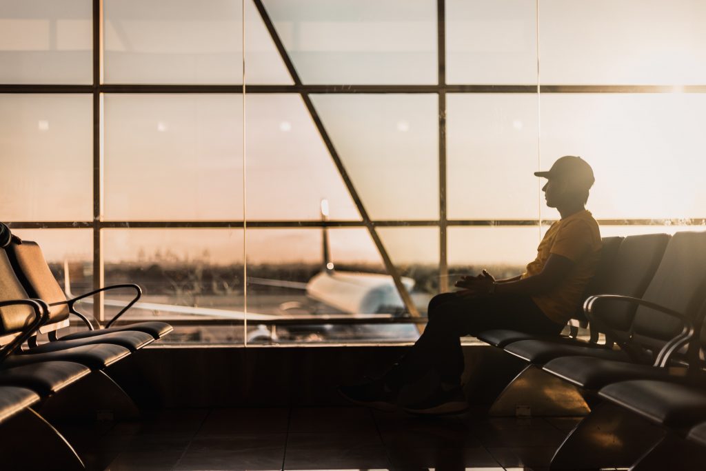 a man sitting alone in an airport during the sunset.