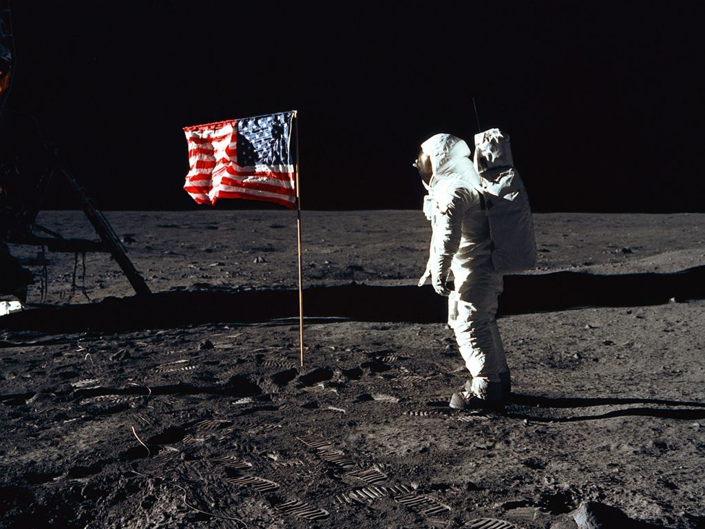 Neil Armstrong in a spacesuit with the American flag on the Moon