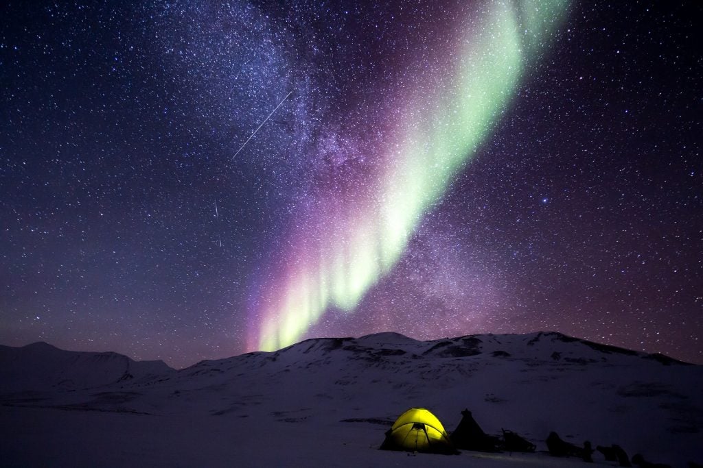 Northern lights and starry sky with a tent 