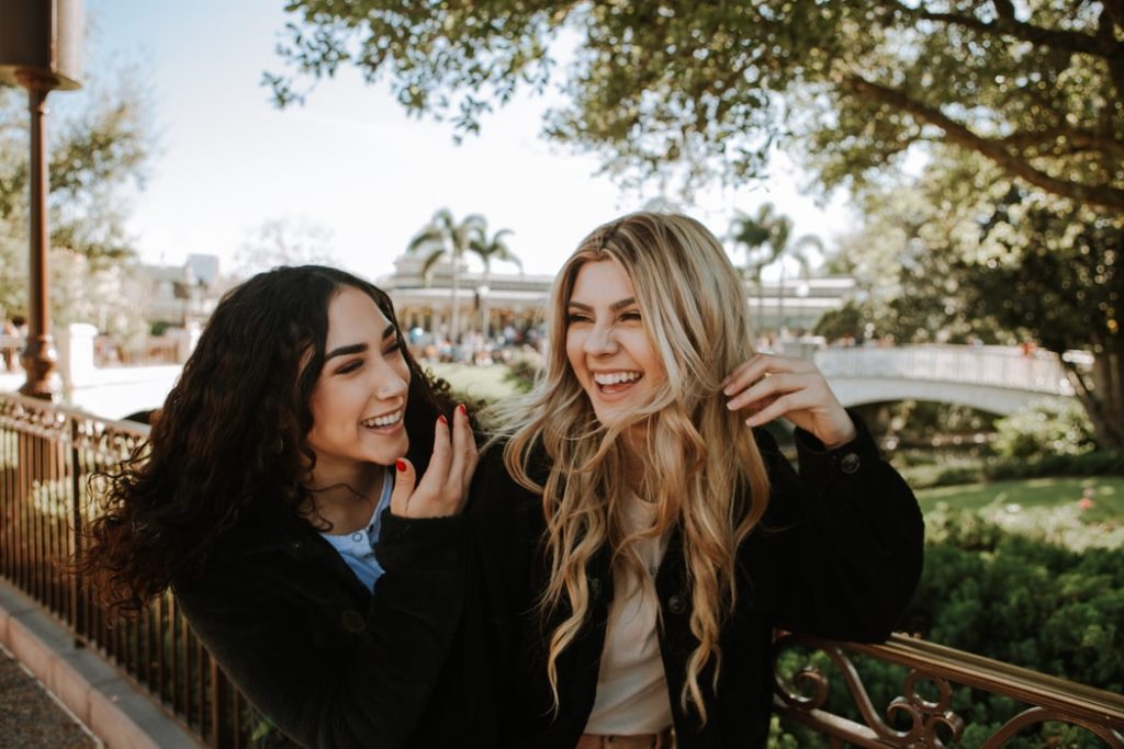 Two young women laughing together in front of the camera because they have found each other as the perfect travel buddy