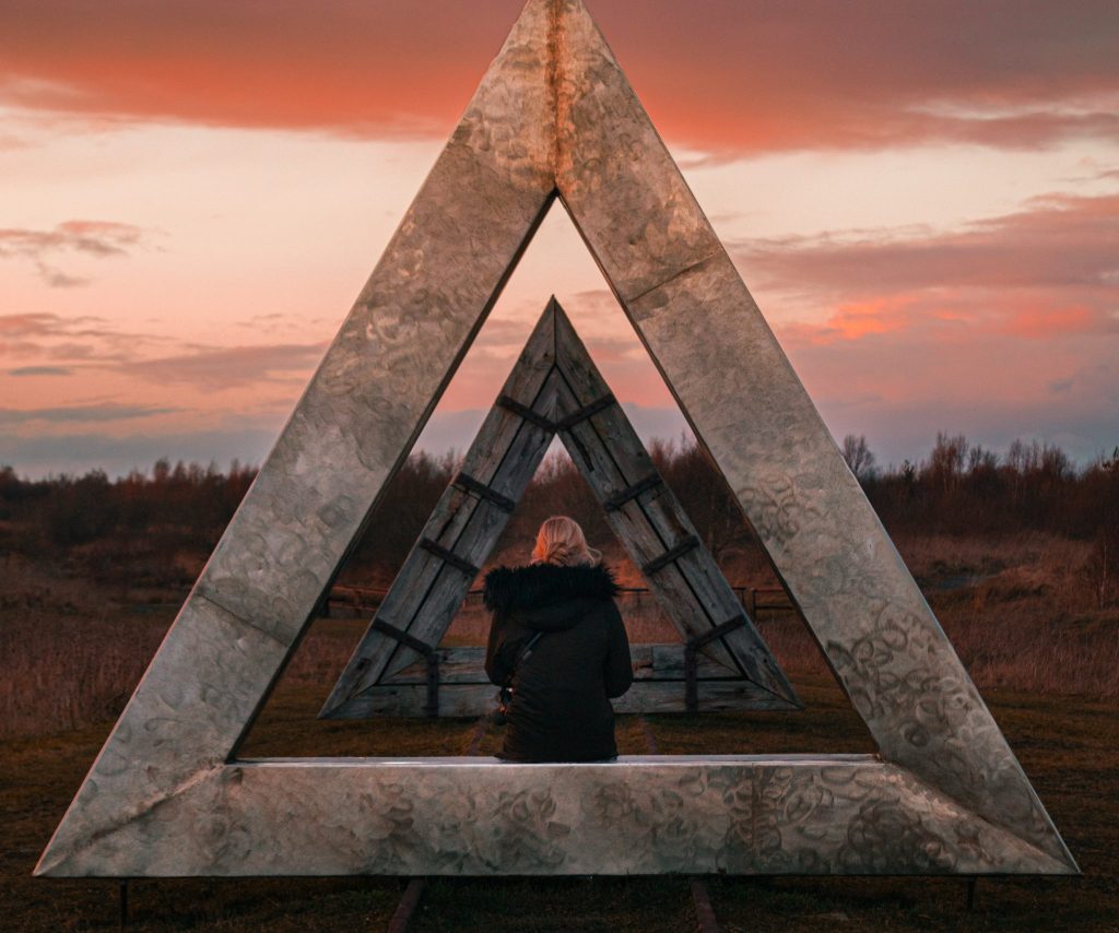 Lough Boora Discovery Park in Ireland with a woman sitting in the middle of a metal triangle.
