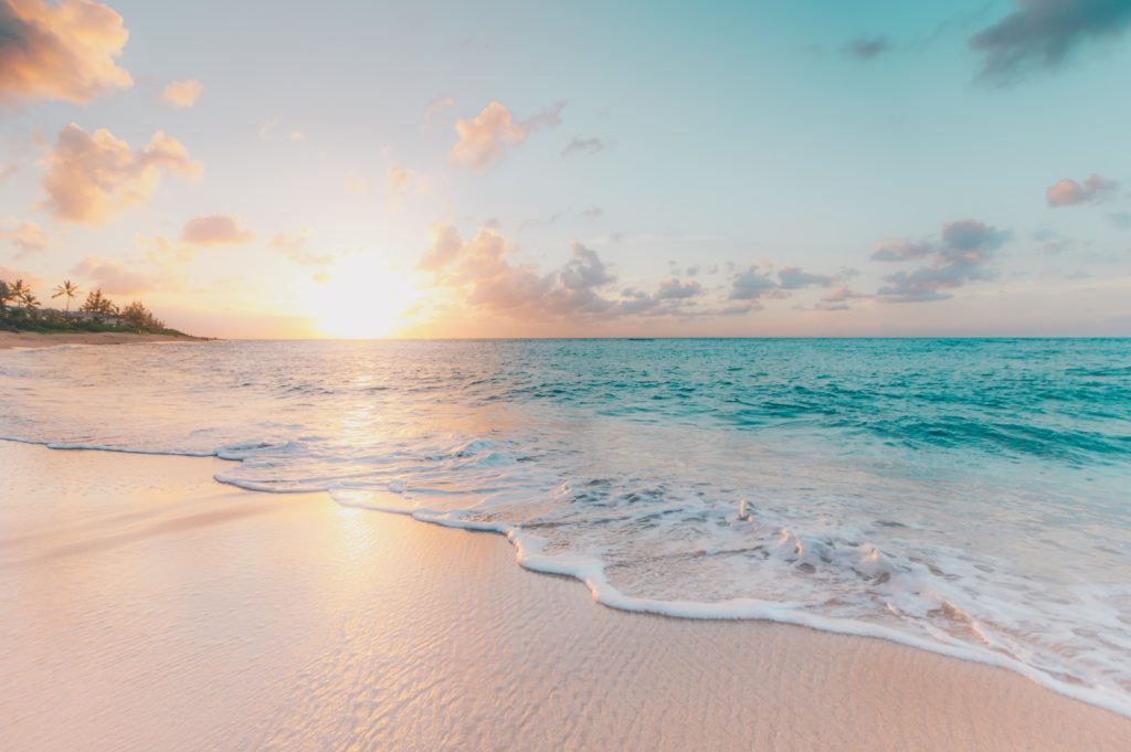 ein Strand in Hawaii mit einer Sonne im Hintergrund 
