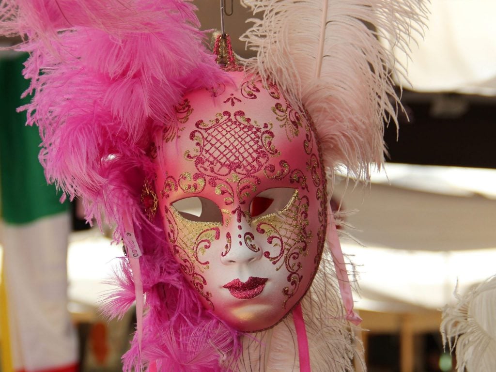 A pink mask with feathers for a costume party.