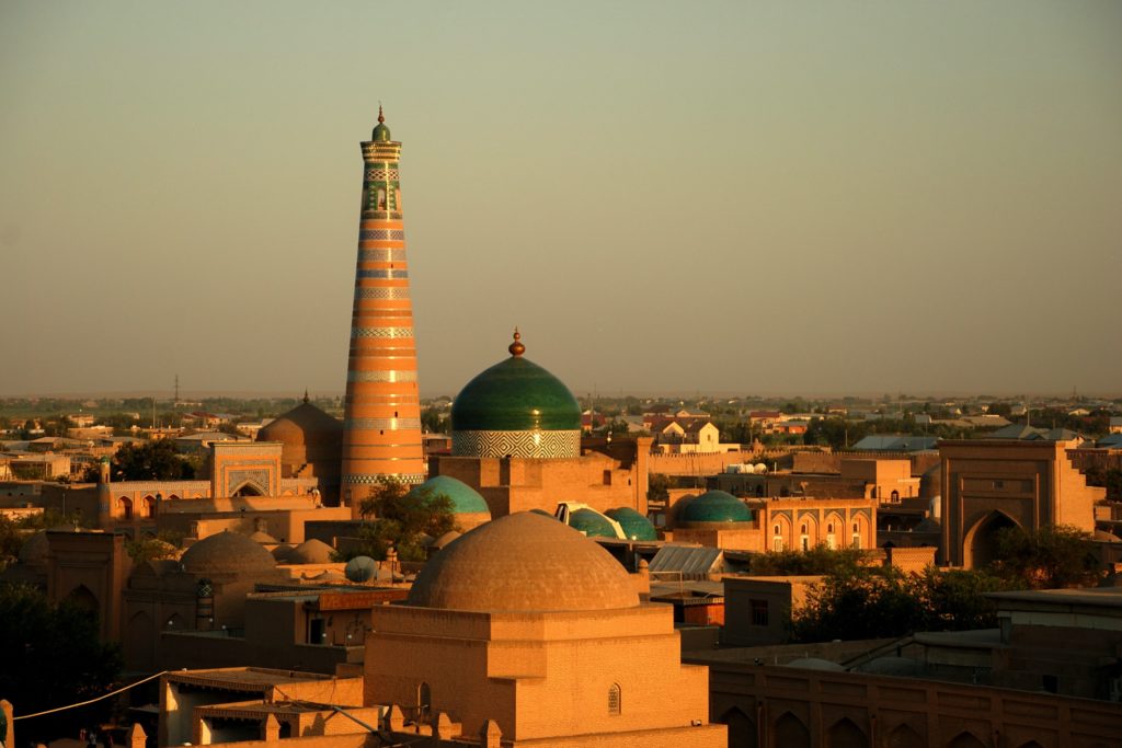 The sunset dives the city samarkand in uzbekistan into a warm orange. In the middle of the city rises a tower above the city and is one of the best places to travel in 2020
