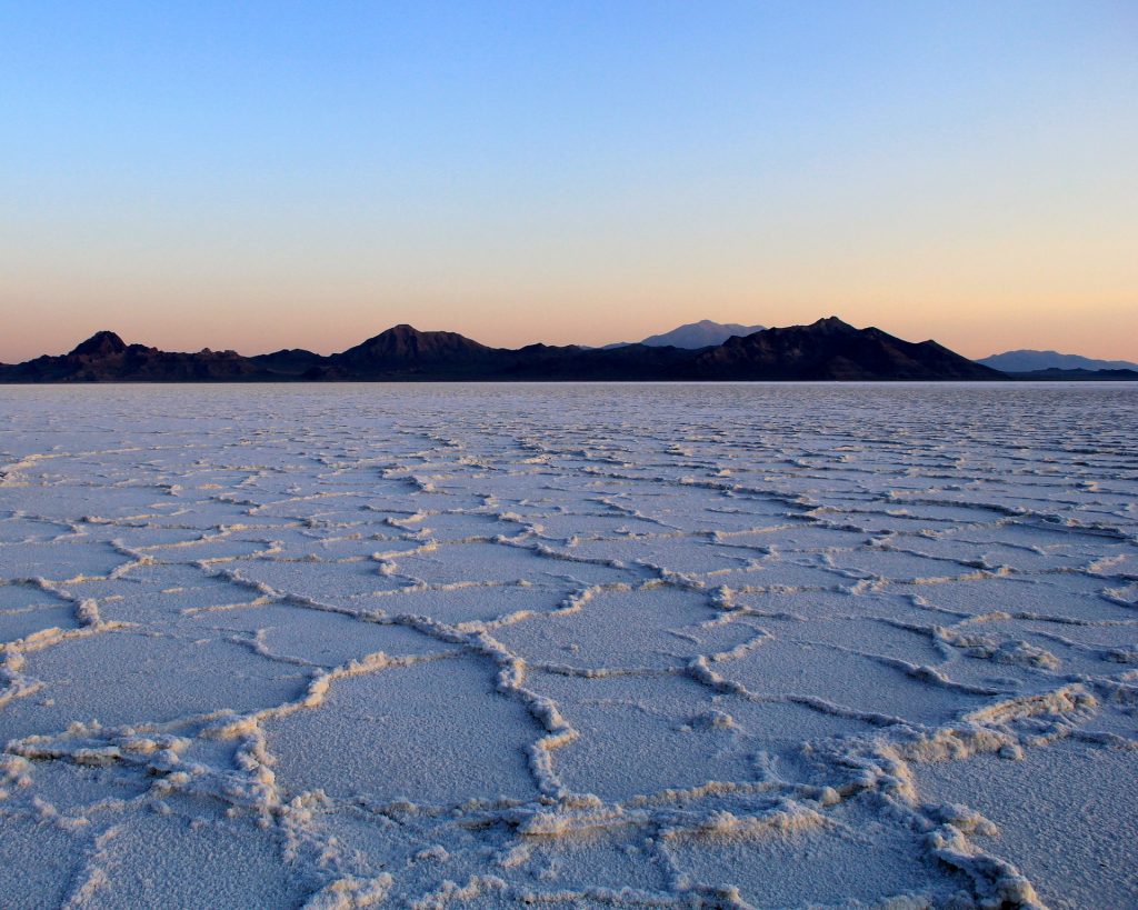 White salt flats with mountains in the background at sunrise
