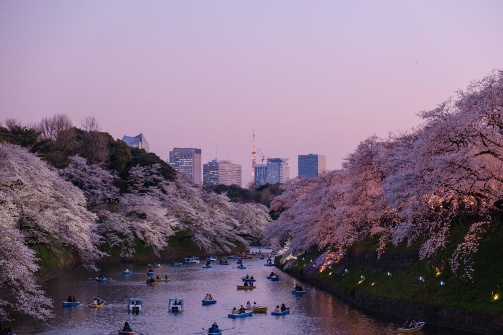 A purple sky over a small river with many small boats and in the background the skyscrapers of tokyo as one of the best places to travel in 2020