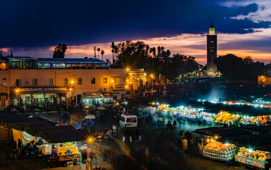Vogelperspektive auf marokkanische Stadt bei Dunkelheit, beleuchtete Stände und Gebäude