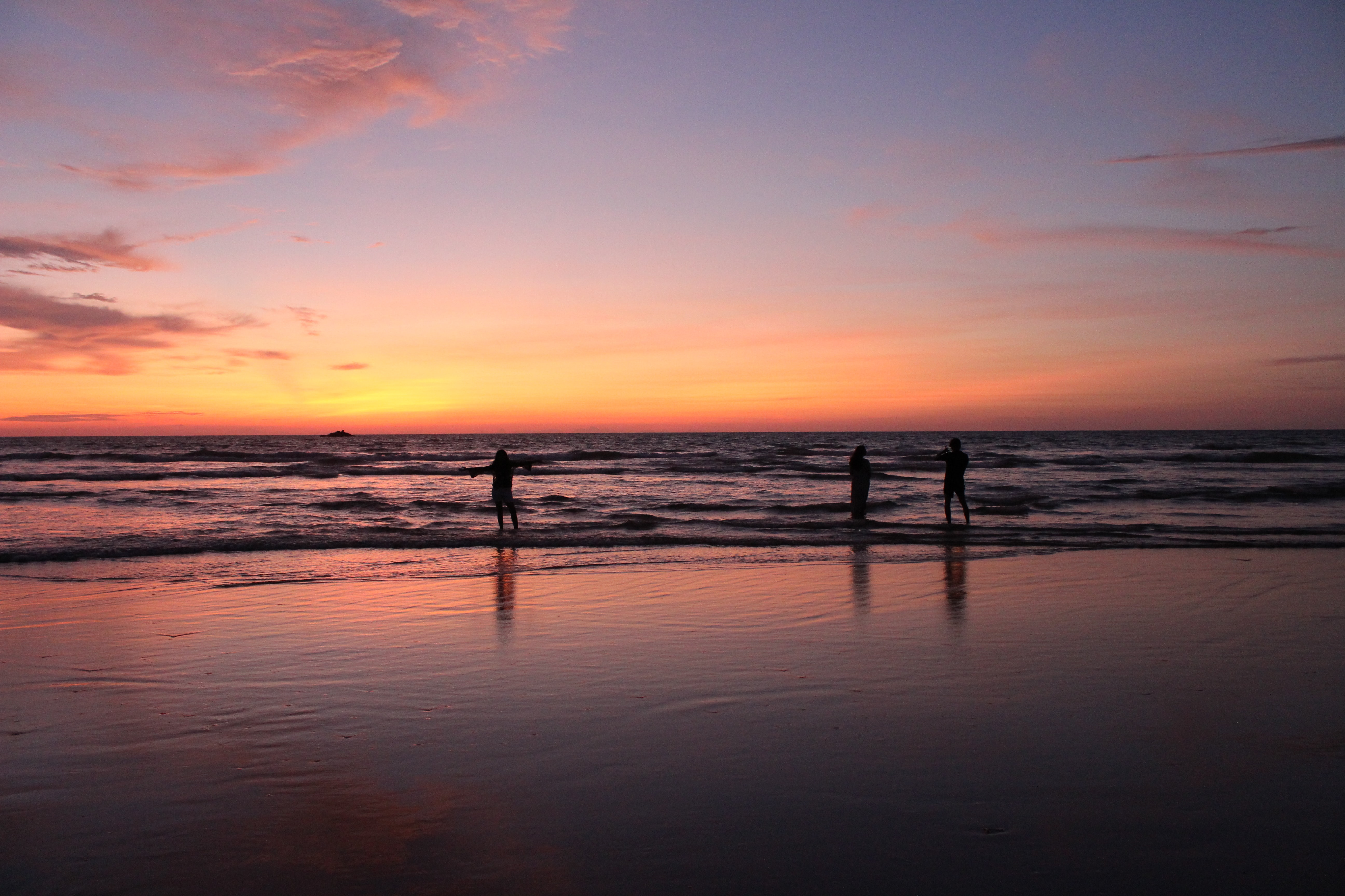 Kudle Strand im Sonnenuntergang mit freudigen Menschen die im Wasser stehen. 