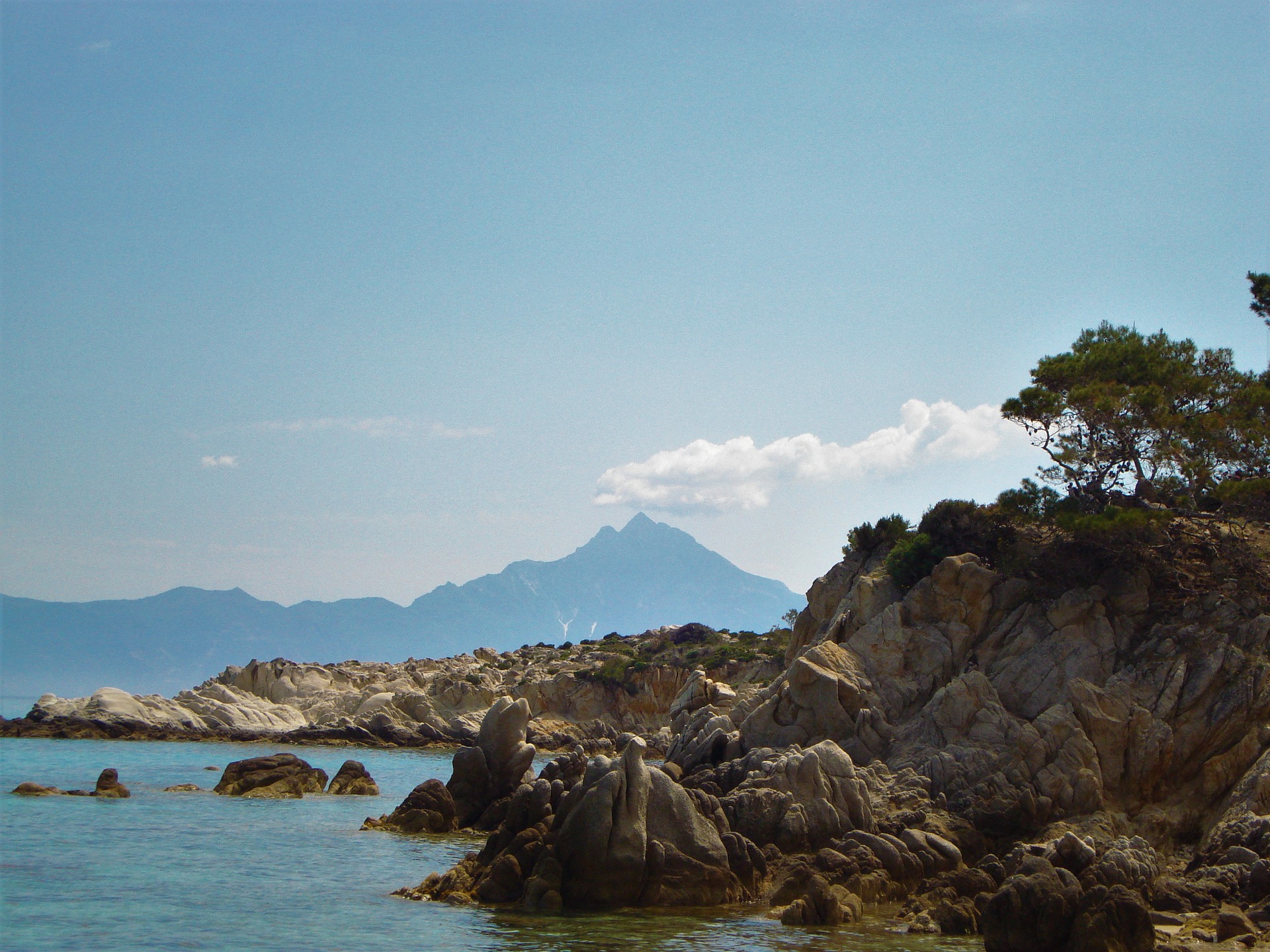 A rocky shore with mountains in the background on a clear day on the Halkidiki coast