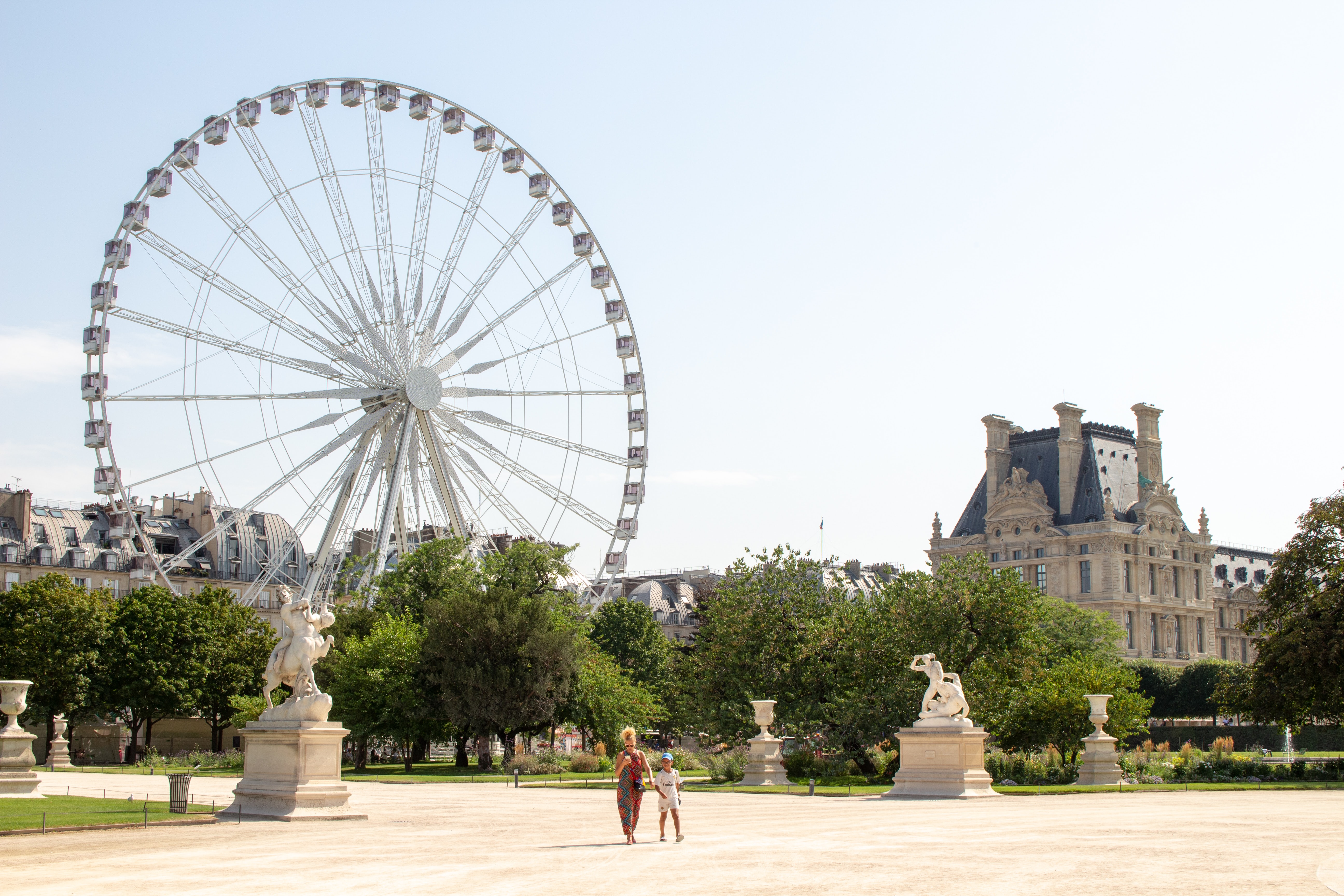 The park Jardin des Tuileries with a Ferris wheel, statues and part of the Louvre buildingl