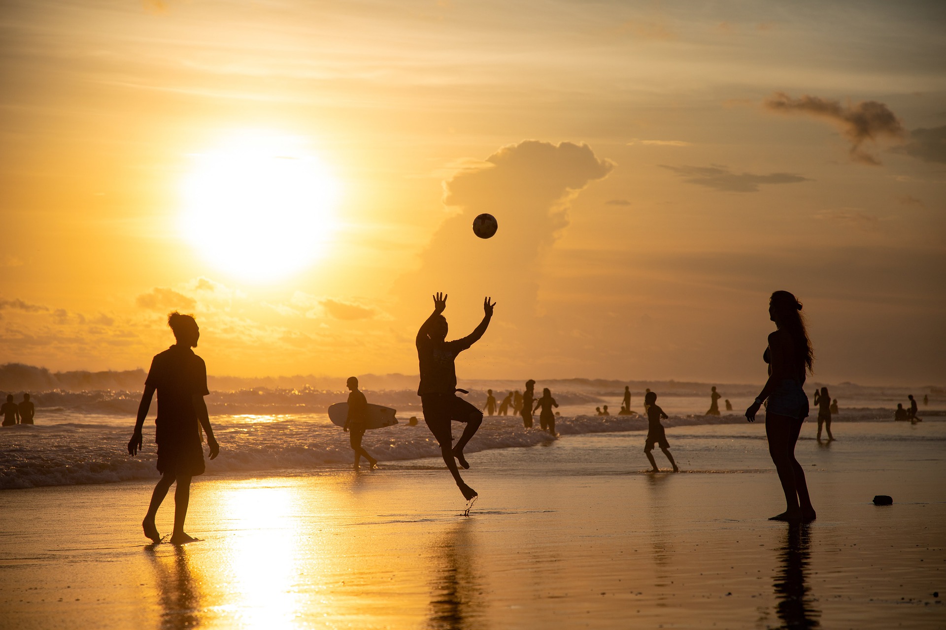 Eine Gruppe spielt Volleyball bei Sonnenuntergang an einem Strand