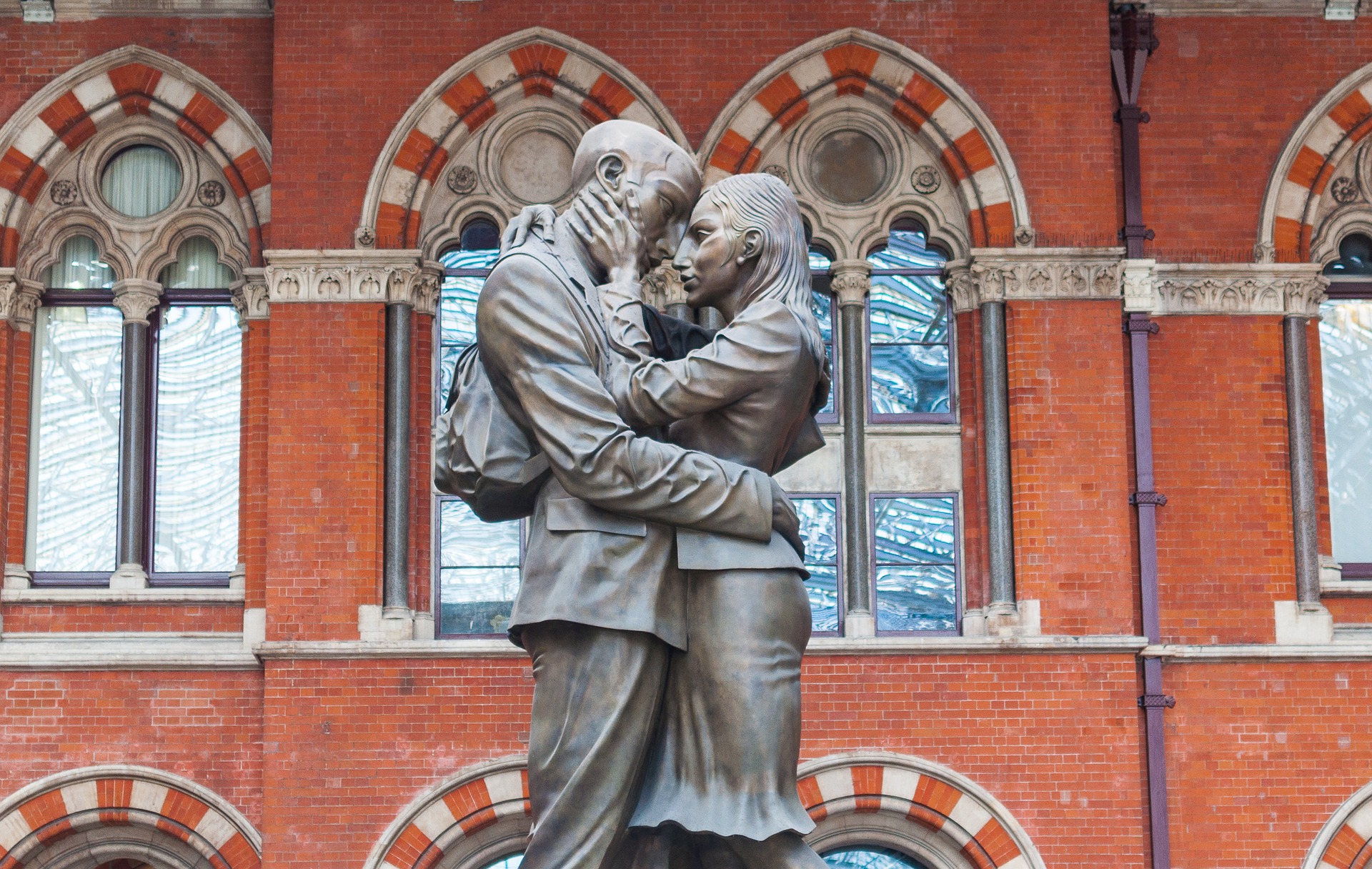 A statue of a woman and man embracing each other at the Gothic style train station of St. Pancras